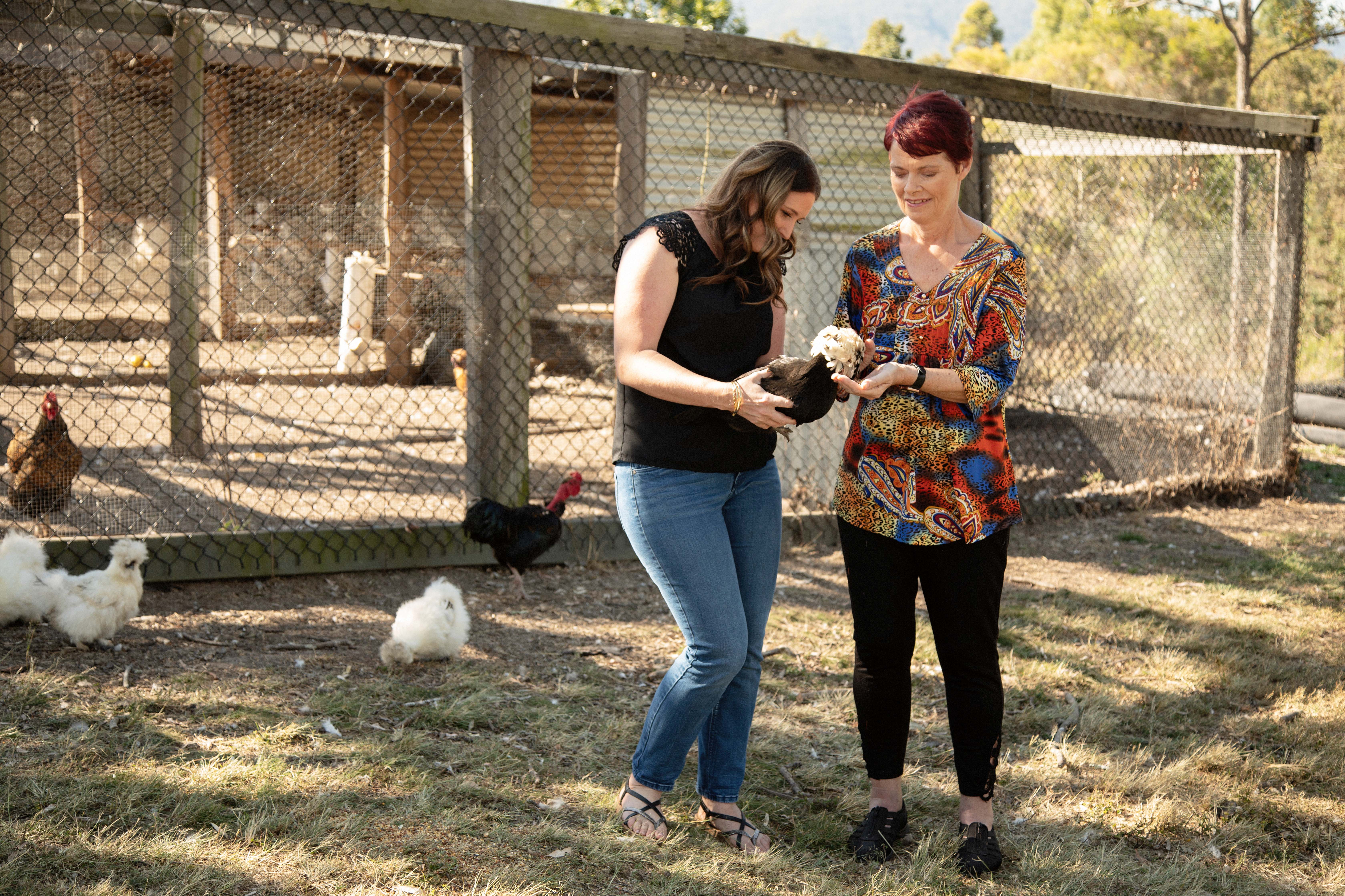 Lady with support worker holding a chicken on a farm