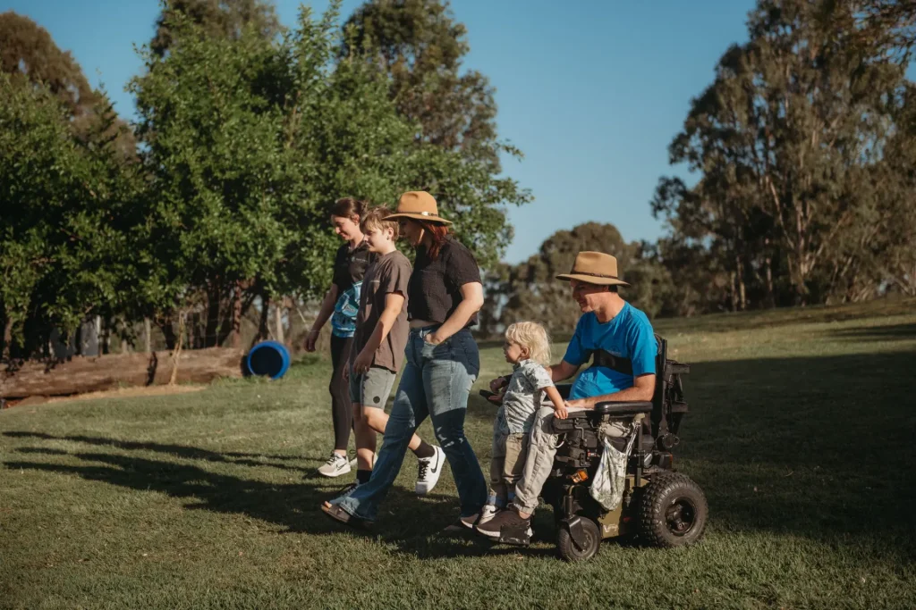 A family and their Quad Care support worker walking the paddock, dog in tow