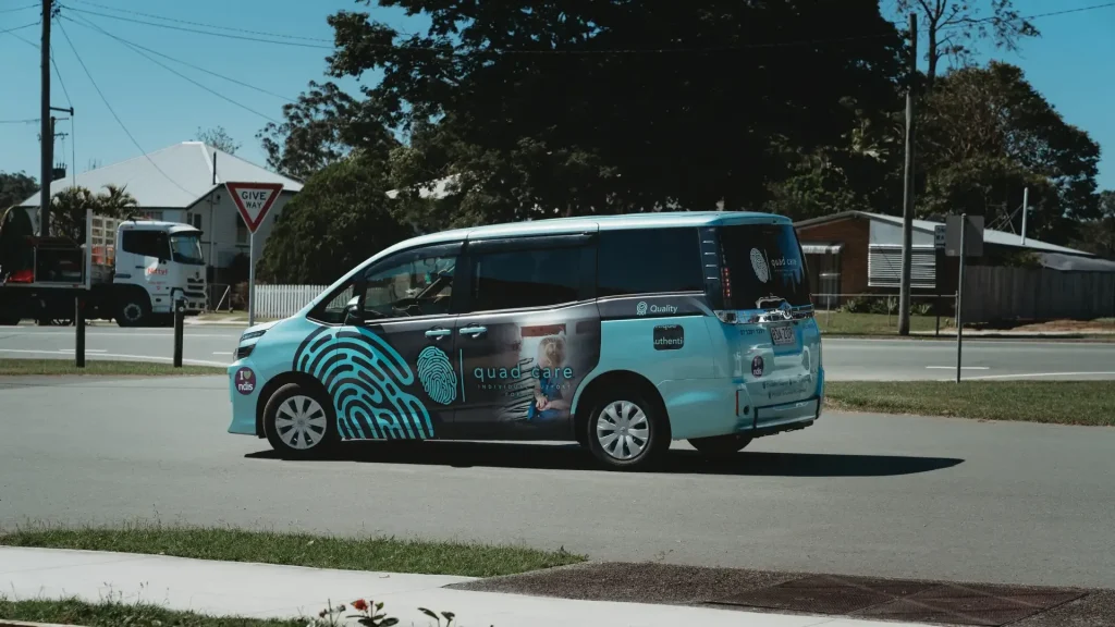Disability support sunshine coast: A Quad Care branded van driving through Woodford on the way to a shift